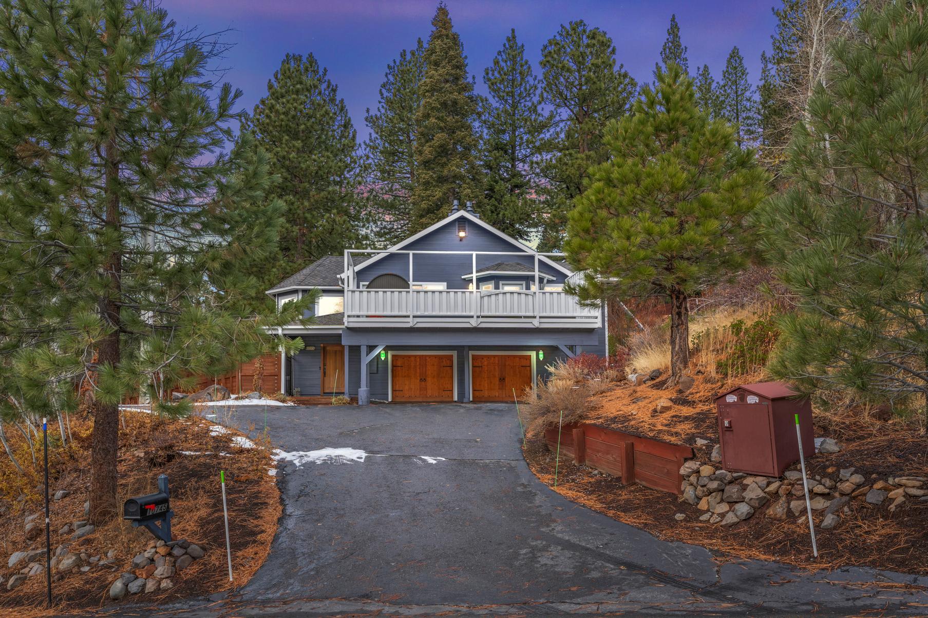 Cozy vacation rental in Truckee surrounded by pine trees, featuring a two-story cabin with a large driveway and balcony.