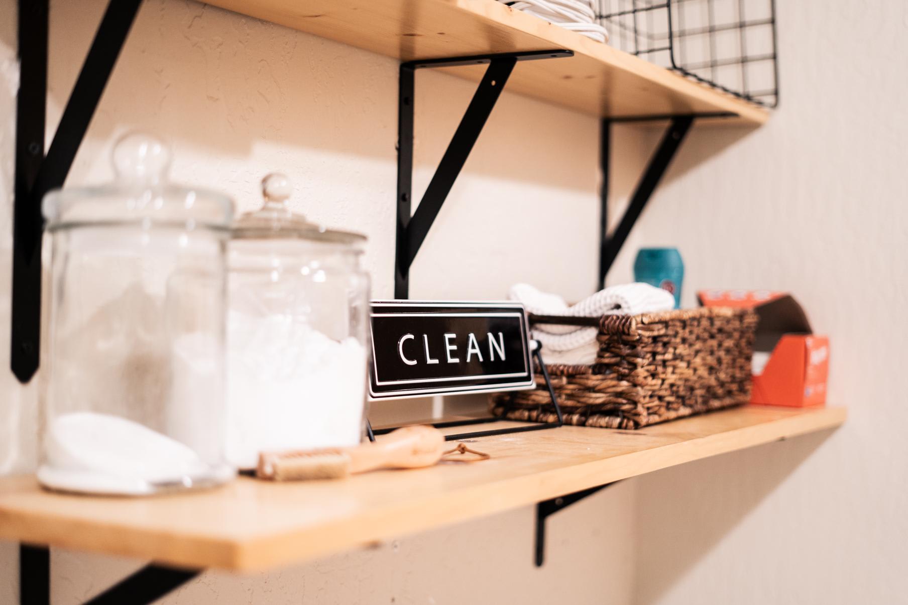 Shelf in a Truckee vacation rental with a "Clean" sign, jars, and a wicker basket on display.