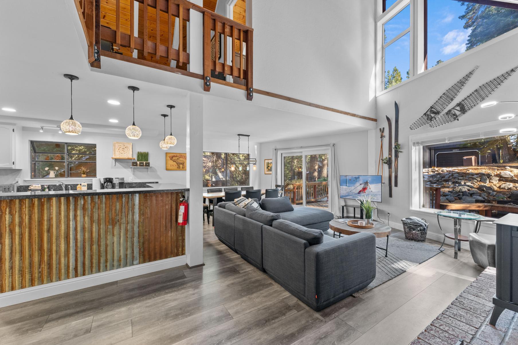 Modern Tahoe Vista vacation rental with a cozy open living area, large windows, and rustic kitchen bar.