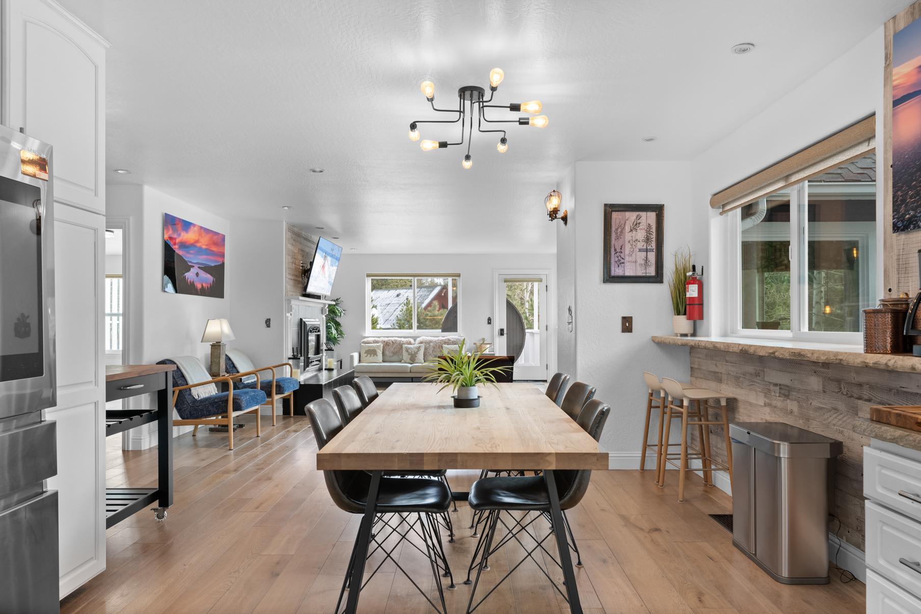 Modern dining area in a Truckee vacation rental, featuring a wooden table, stylish chairs, and cozy living room.