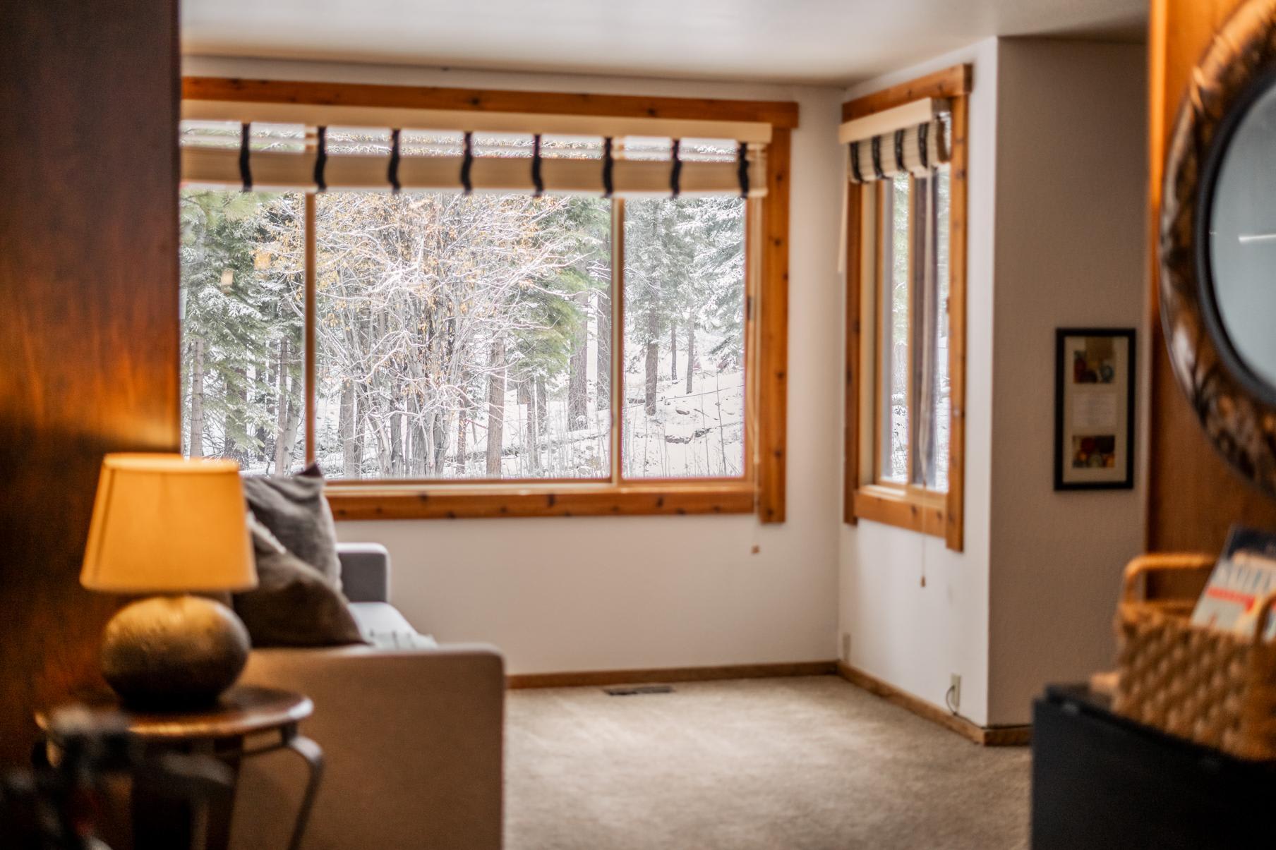 Cozy Truckee vacation rental interior with large windows overlooking a snowy forest scene.