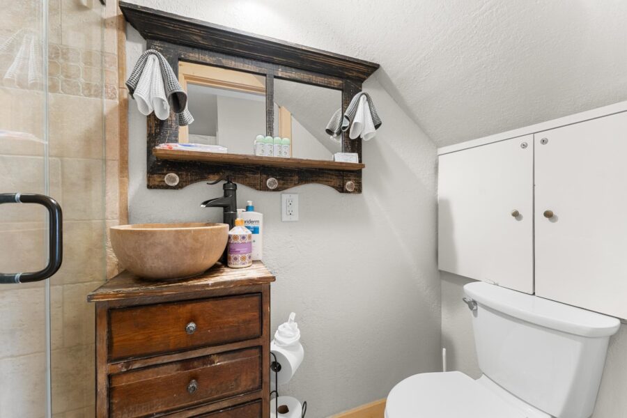 Rustic bathroom in a Truckee vacation rental with a wooden vanity, modern vessel sink, and a walk-in shower.