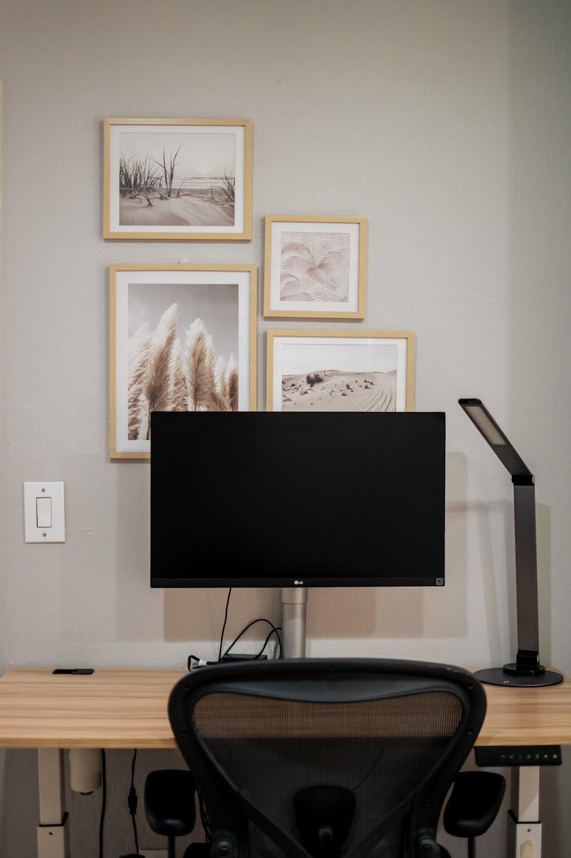 A modern desk setup in a Truckee vacation rental with artwork above the monitor on a beige wall.