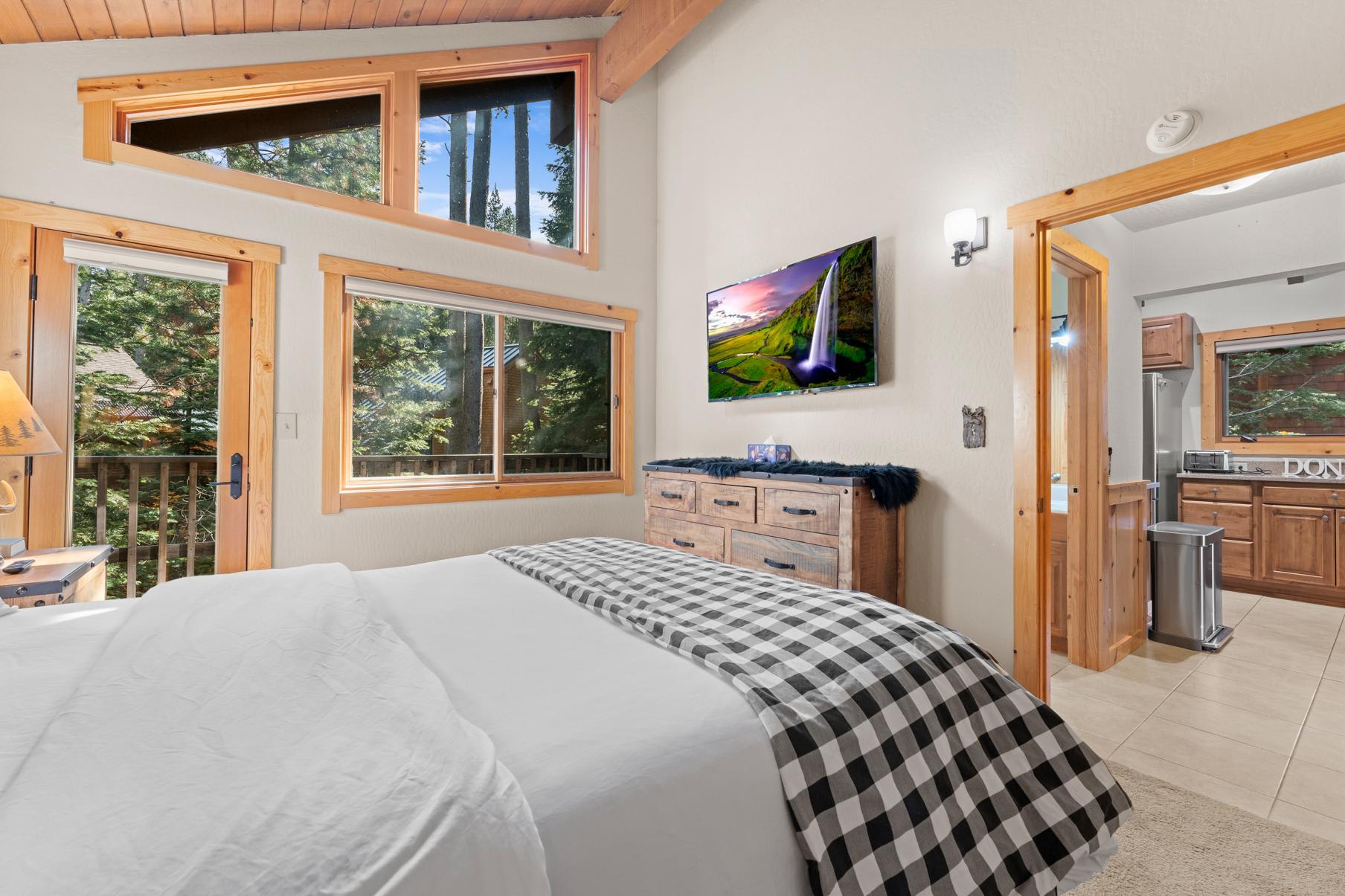 Bedroom in a Truckee vacation rental with wood accents, large windows, and forest views. Cozy and inviting space.