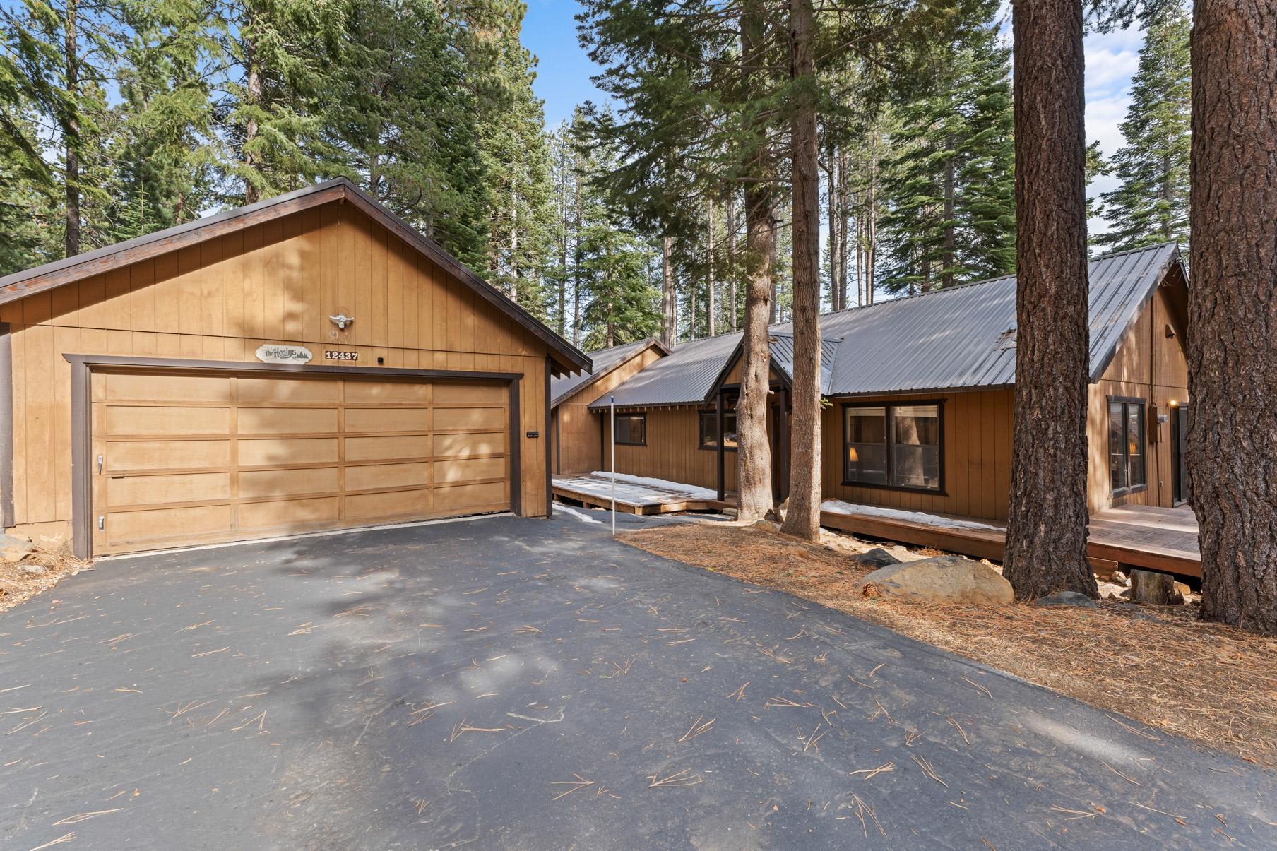 Rustic vacation rental cabin in Truckee, surrounded by tall pine trees, featuring a wooden exterior and a large garage.