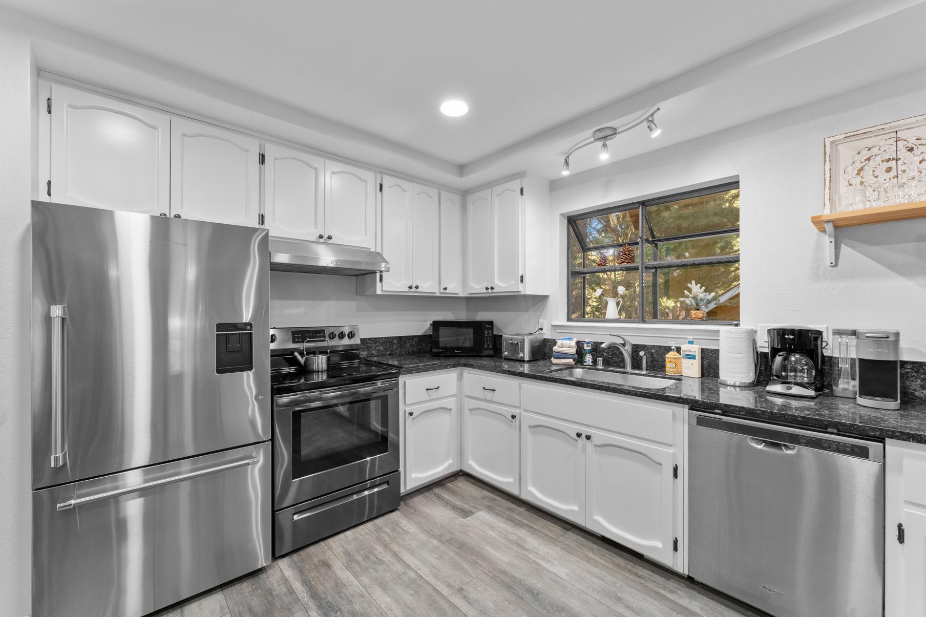 Modern kitchen in a Tahoe Vista vacation rental with stainless steel appliances and white cabinetry.