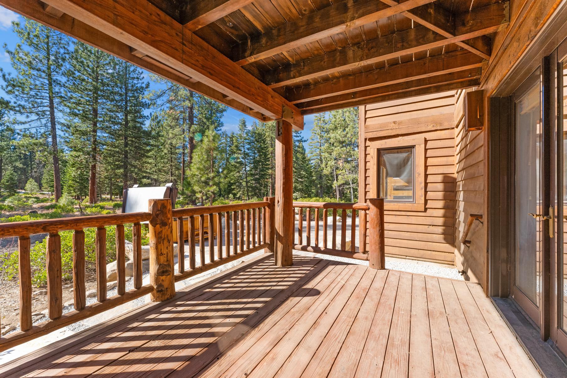 Wooden deck of a Truckee vacation rental overlooking a forest with tall pine trees on a sunny day.