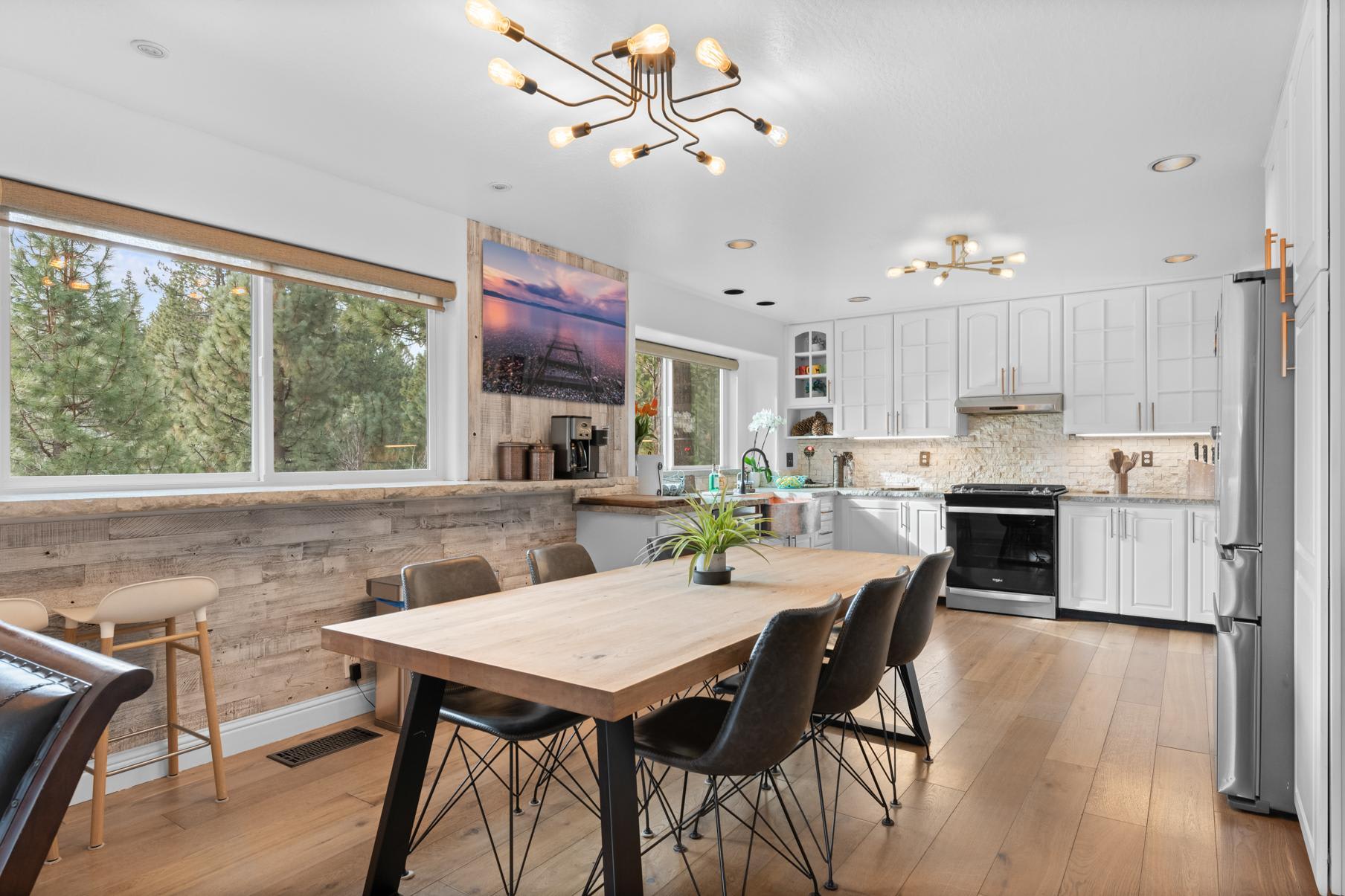 Modern kitchen in Truckee vacation rental, featuring white cabinets, wooden dining table, and scenic forest views.