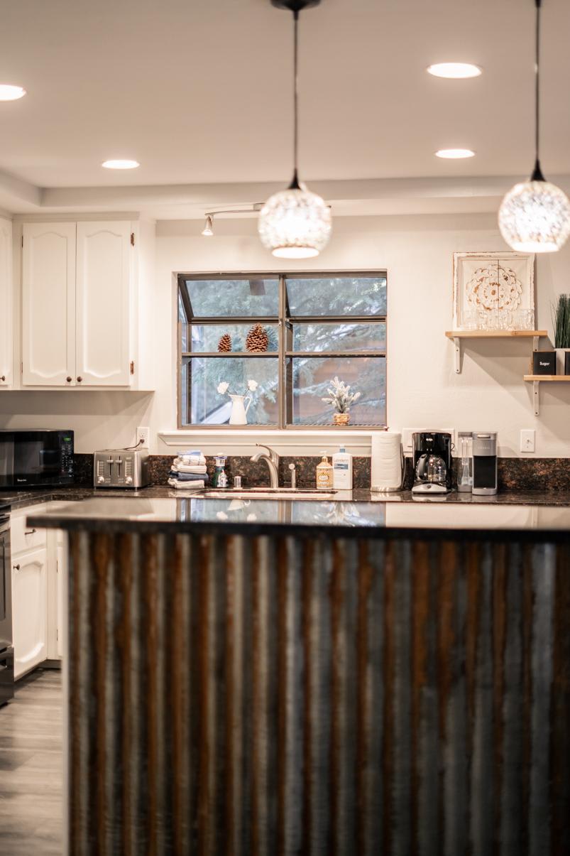 Modern kitchen in Tahoe Vista vacation rental with hanging lights, rustic island, and window view.