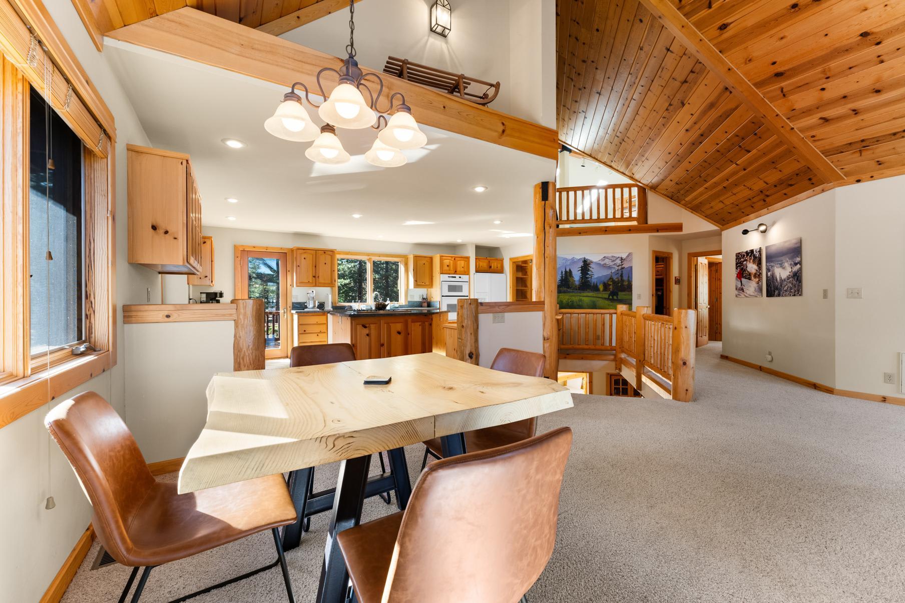 Rustic Truckee vacation rental featuring wood accents, open kitchen, and cozy dining area with leather chairs.