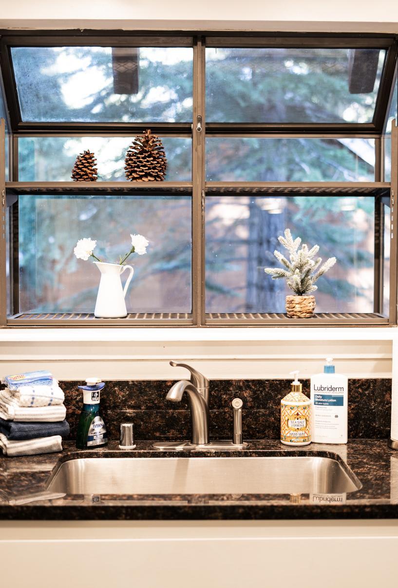 Kitchen sink view in a Tahoe Vista vacation rental featuring pinecones and decor on the window ledge.