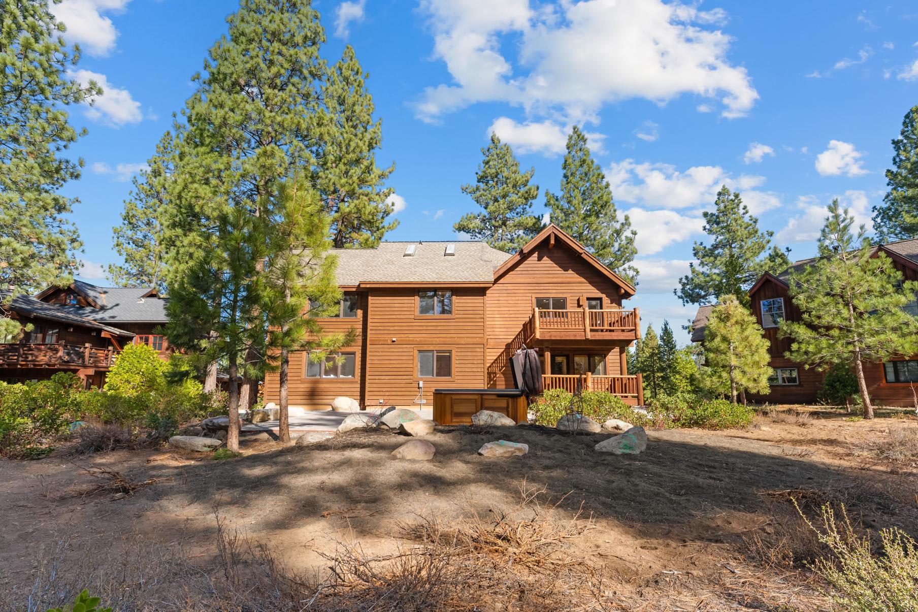 Wooden vacation rental cabin surrounded by trees in Truckee under a blue sky.