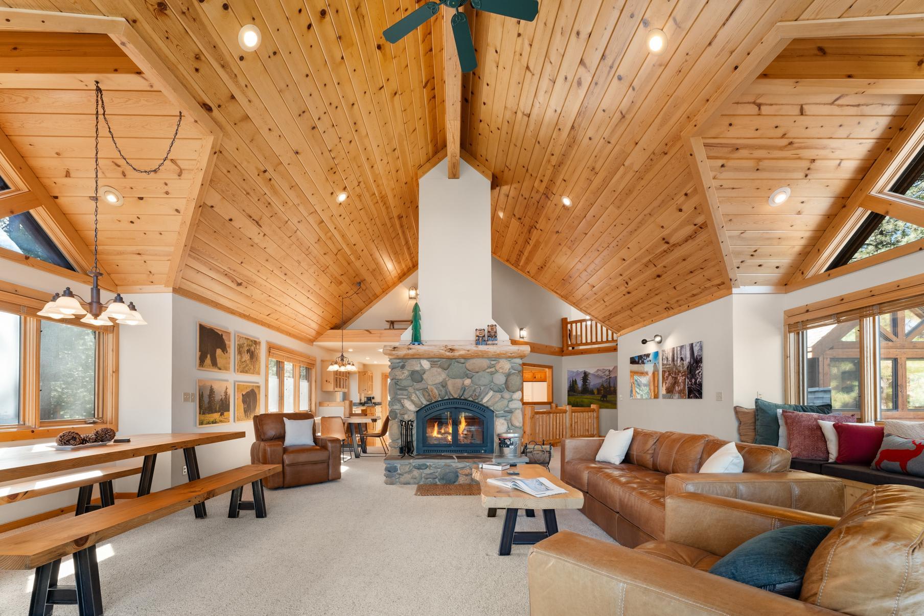 Rustic living room in a Truckee vacation rental featuring wooden ceilings, stone fireplace, and cozy leather seating.