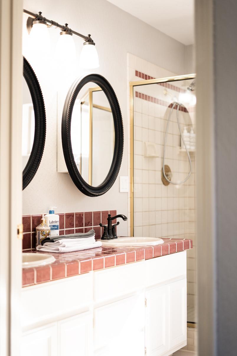 Bathroom in a Truckee vacation rental, featuring a sink with red tile countertop and a shower with glass door.