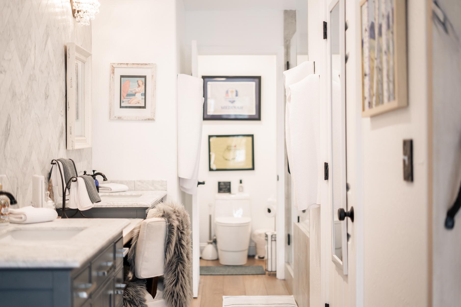 Bright, modern bathroom in a Truckee vacation rental, featuring marble countertops, art, and cozy seating.