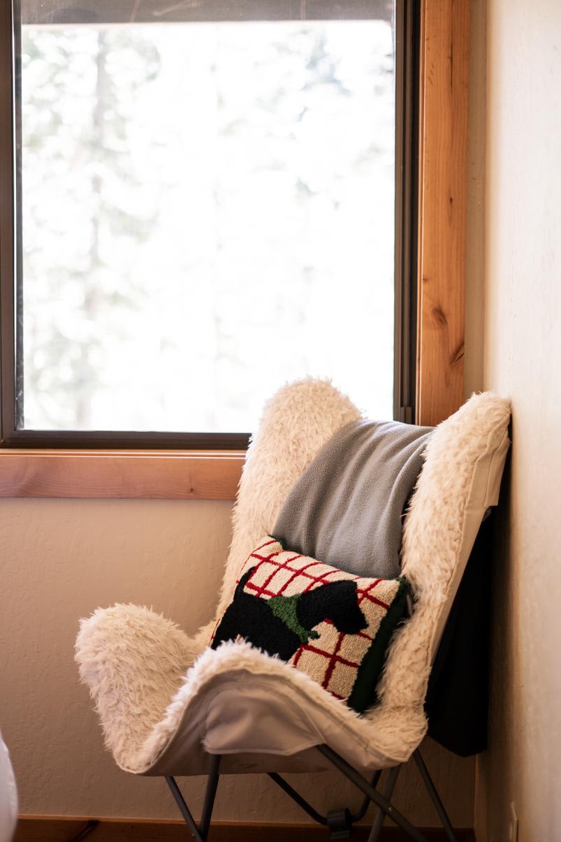 Cozy corner in Truckee vacation rental with a plush chair, decorative pillow, and soft blanket by a sunny window.