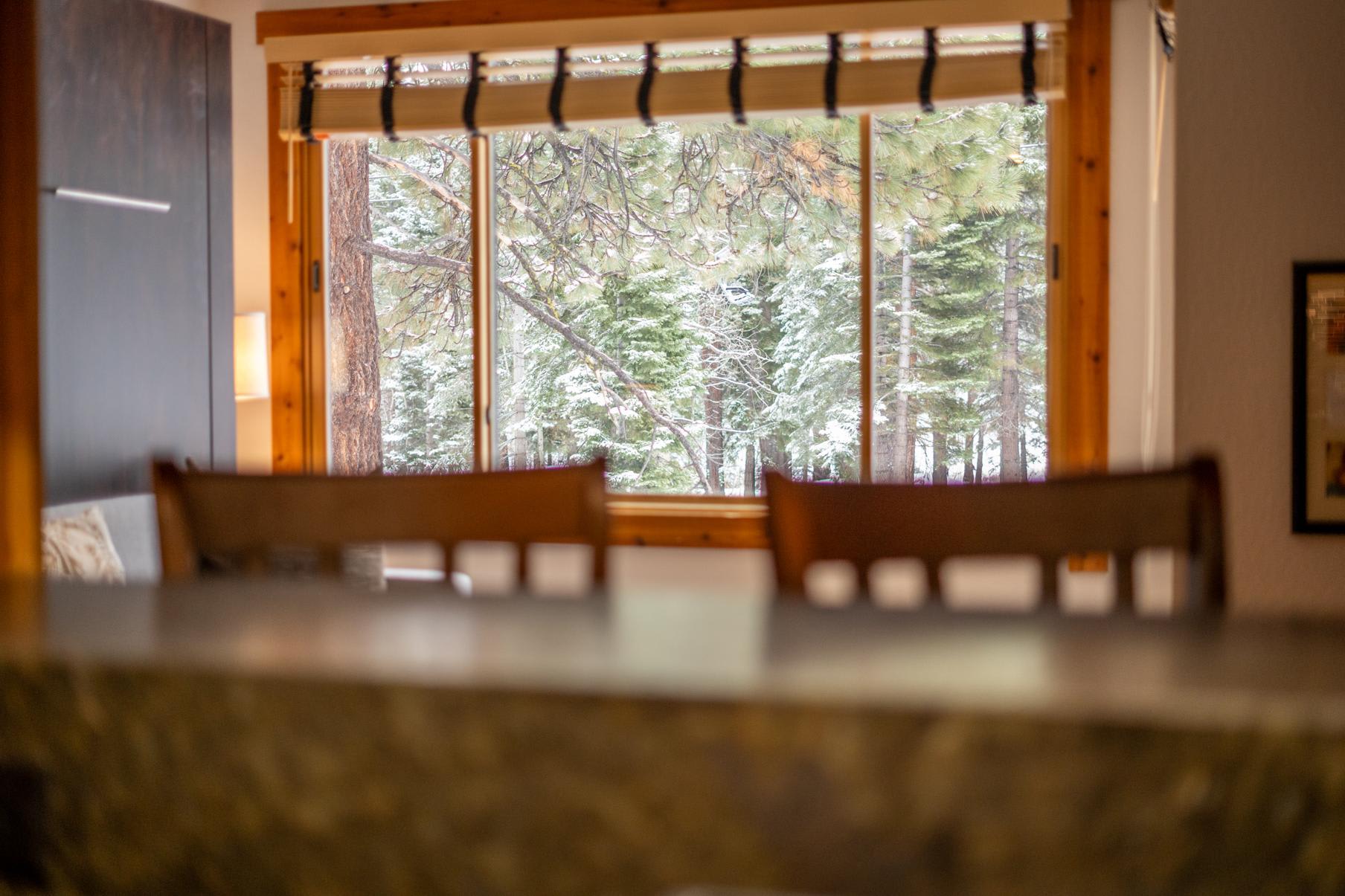 Cozy Truckee vacation rental with forest view through large window, wooden accents, and soft lighting.