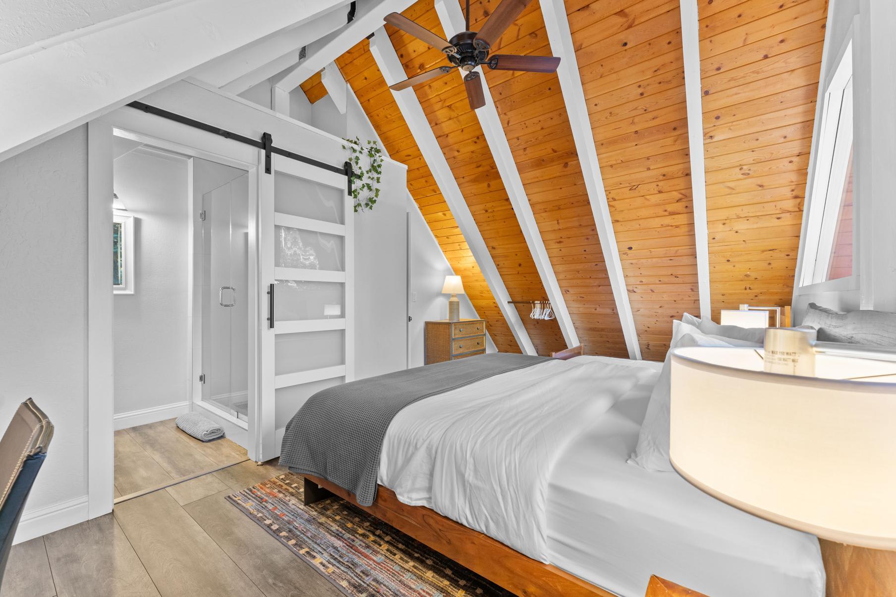 Cozy attic bedroom with wooden ceiling in a Tahoe Vista vacation rental, featuring a modern design and sliding glass door.