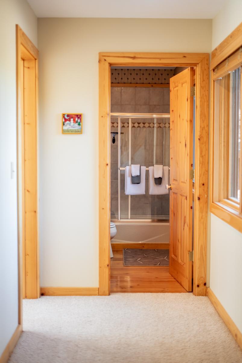 Hallway leading to a bathroom with wooden trim in a Truckee vacation rental.