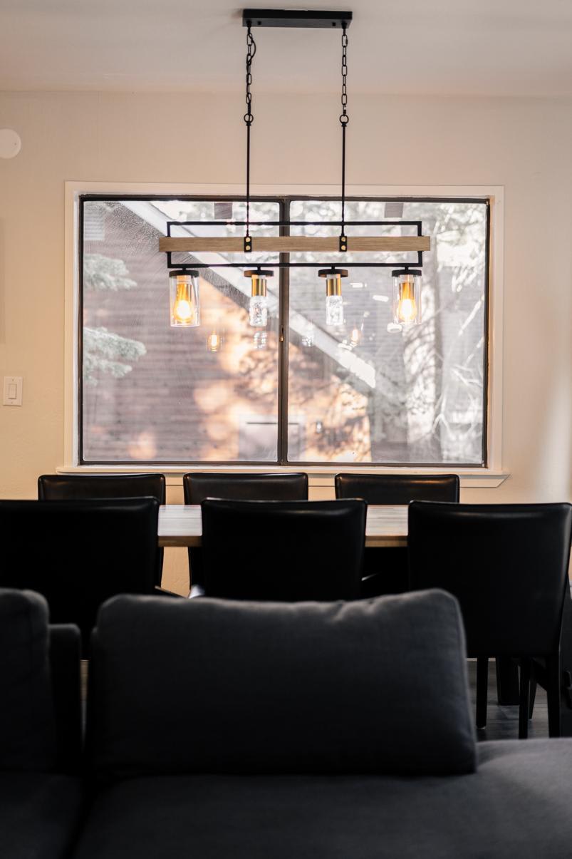 Modern dining area in a Tahoe Vista vacation rental featuring a rustic chandelier and large window view.