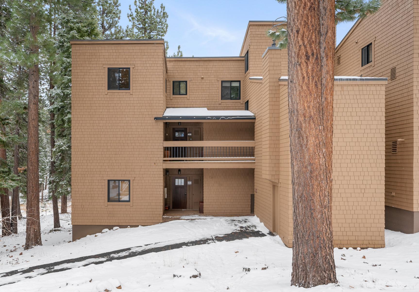 Brown vacation rental in snowy Truckee, surrounded by tall pine trees.