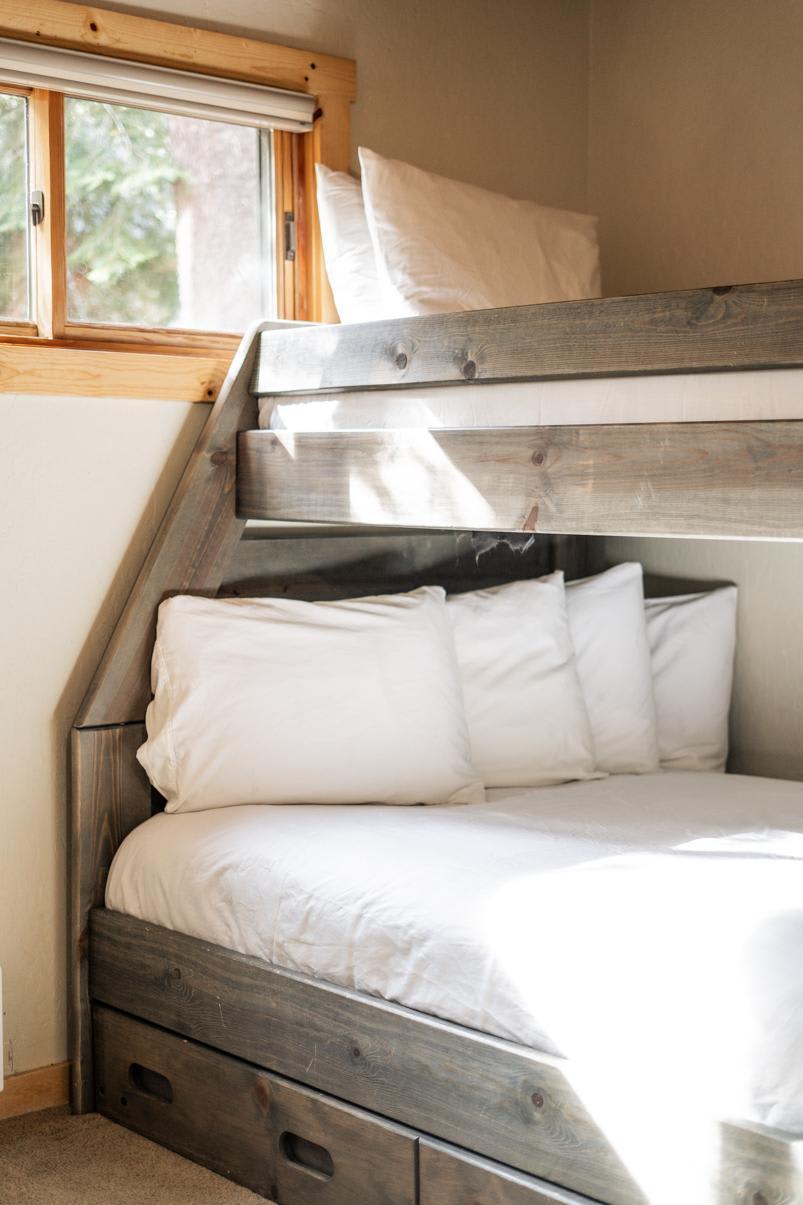 Cozy bedroom with a wooden bunk bed in a Truckee vacation rental, featuring white bedding and soft natural light.