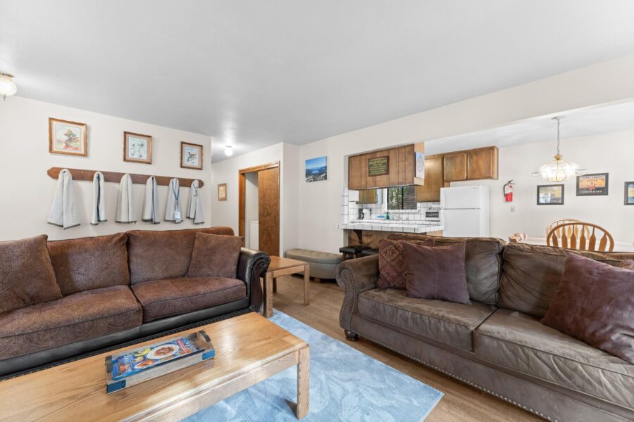 Cozy Truckee vacation rental living room with brown sofas, wooden table, and open kitchen in the background.