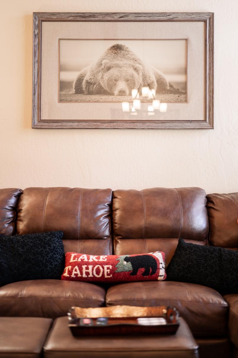 Cozy Truckee vacation rental with leather couch, bear art, and Lake Tahoe-themed pillow.