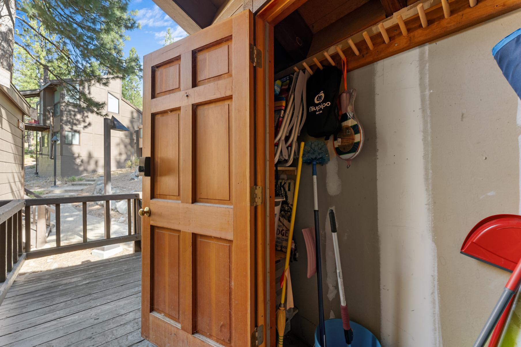 Open closet with cleaning supplies on the deck of a Truckee vacation rental, surrounded by trees and neighboring homes.