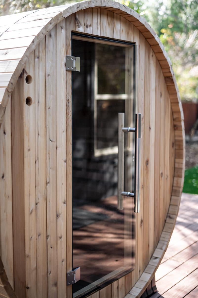 Wooden barrel sauna on a deck at a Truckee vacation rental surrounded by trees.