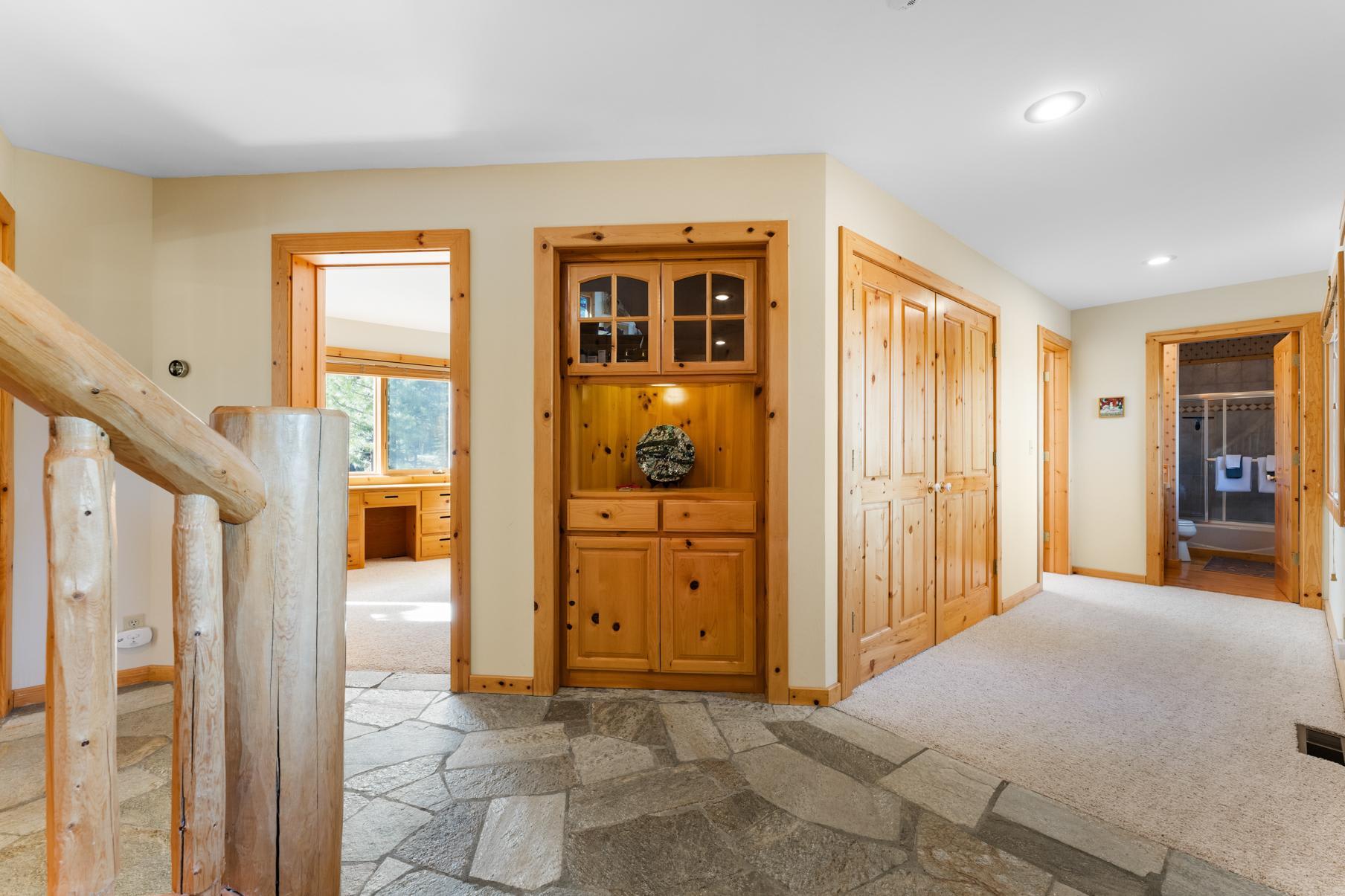 Wood-paneled hallway with stone floor in a Truckee vacation rental, featuring built-in shelves.