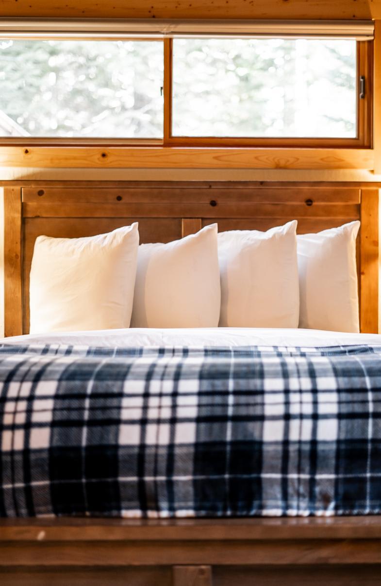 Cozy bedroom in a Truckee vacation rental with a wooden bed, white pillows, and a plaid blanket.