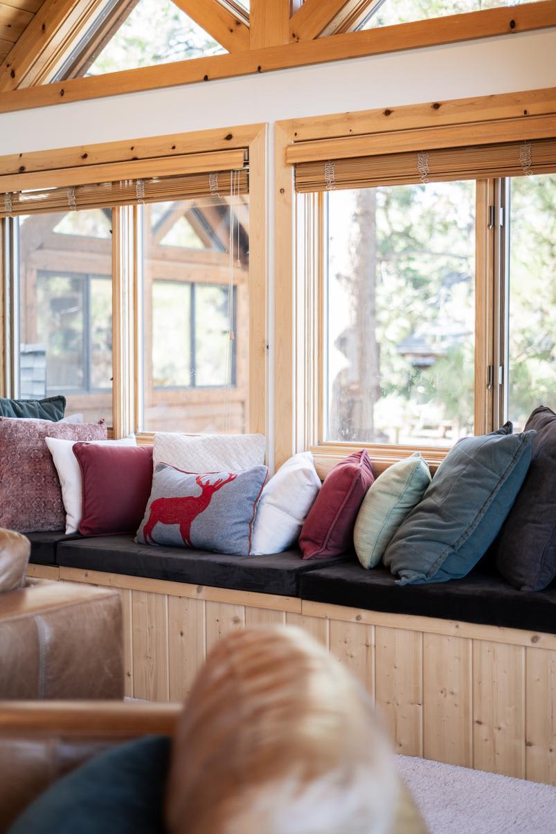 Cozy window seat with colorful pillows in a Truckee vacation rental, featuring wood accents and large sunlit windows.