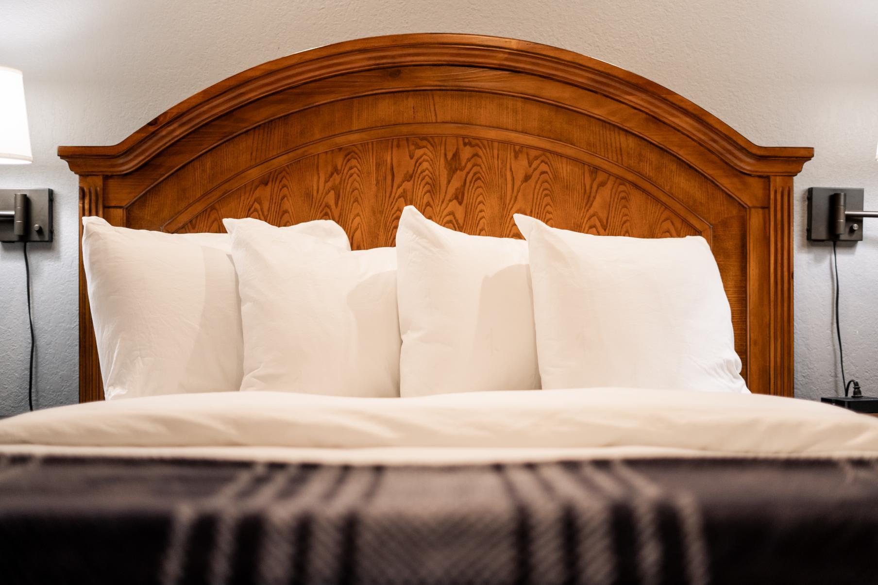 Cozy bed with wooden headboard in a Truckee vacation rental, featuring soft white pillows and warm lighting.