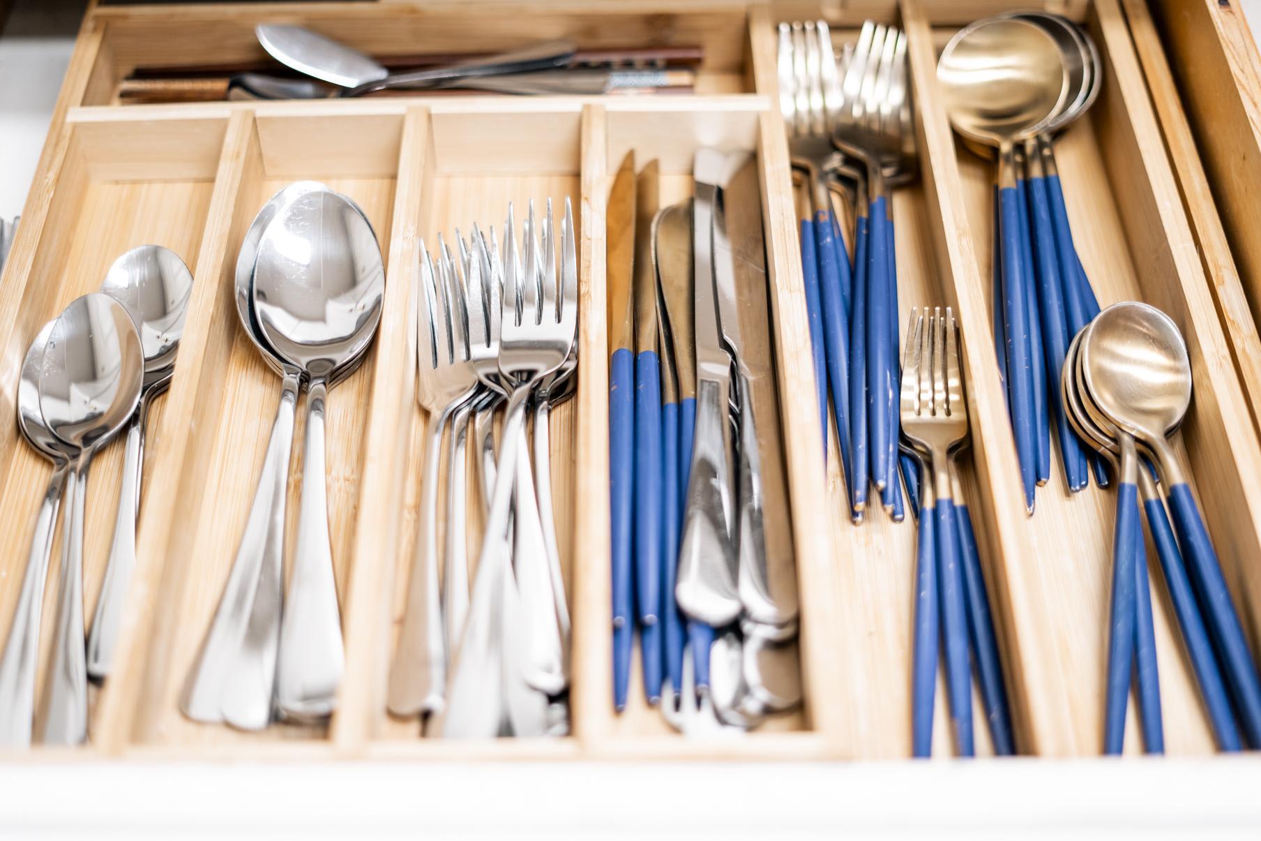 Organized utensils in a drawer at a Truckee vacation rental, featuring blue-handled cutlery in a wooden organizer.