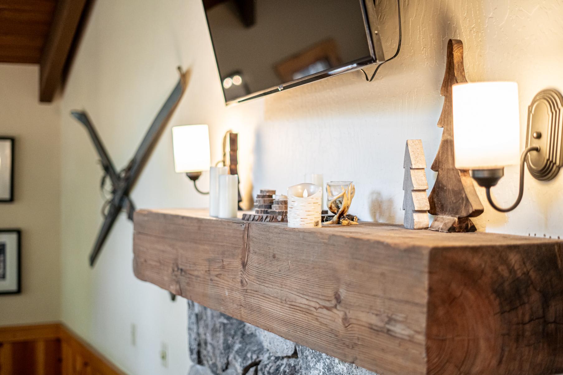 Cozy fireplace mantel in Truckee vacation rental with rustic decor, lit candles, and a wall-mounted TV above.