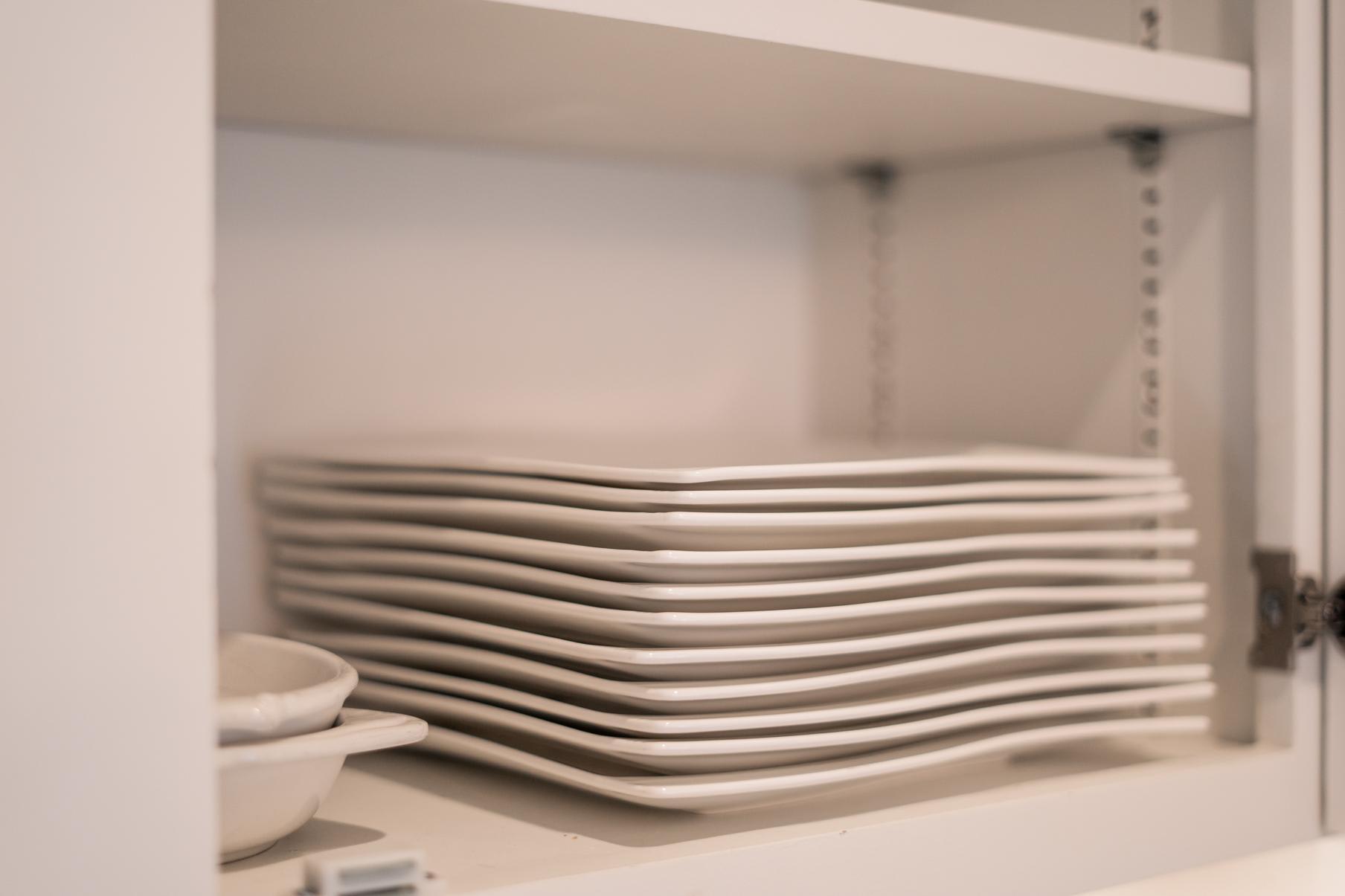 Stack of white plates in a kitchen cabinet of a Truckee vacation rental, showcasing clean and neat organization.