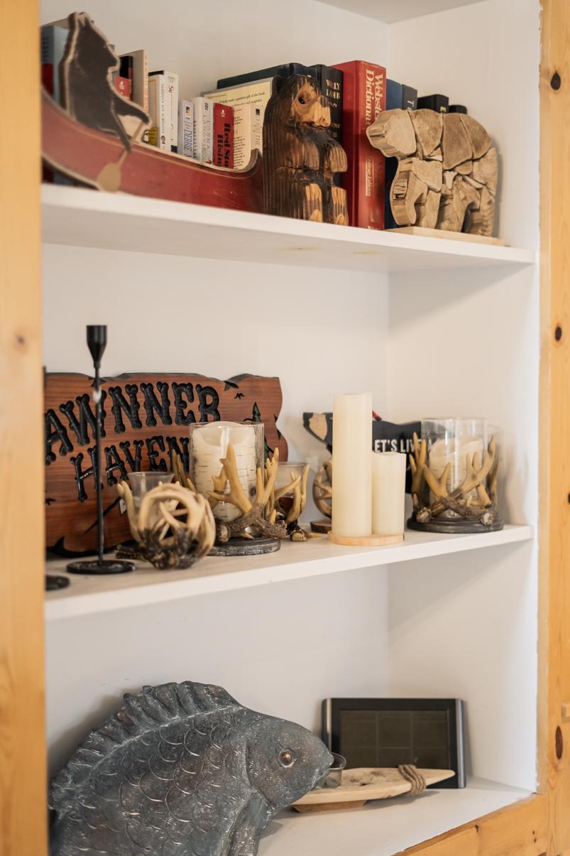 Books and bear decor on shelves in a Truckee vacation rental, featuring antler candle holders and rustic accents.