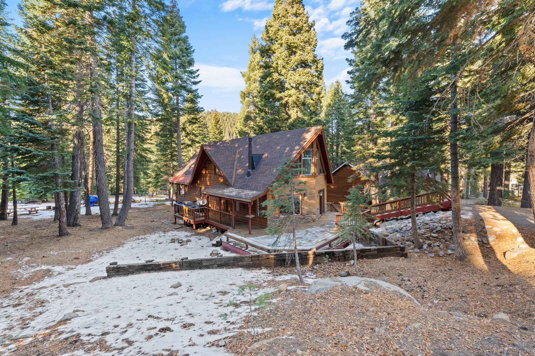 A cozy cabin vacation rental surrounded by tall pines in Tahoe Vista, set on a snowy, picturesque landscape.