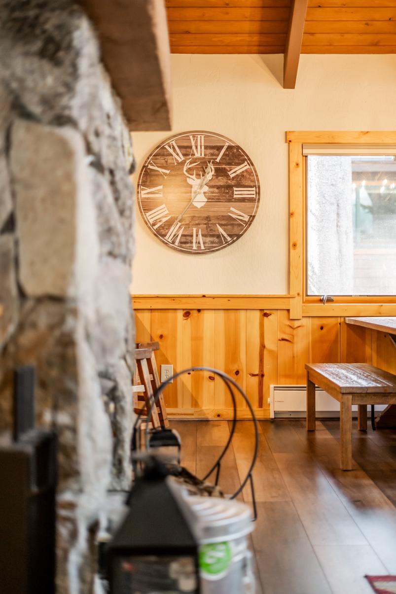 Cozy interior of a Truckee vacation rental with a stone fireplace, wooden clock, and warm wood paneling.