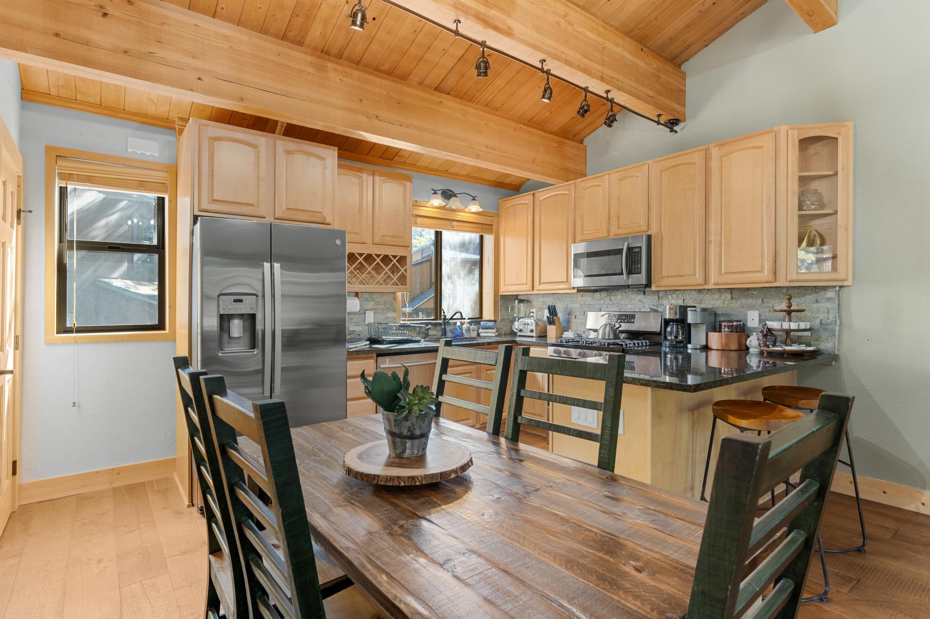 Cozy kitchen in Truckee vacation rental features wooden cabinets, stainless steel appliances, and a rustic dining table.