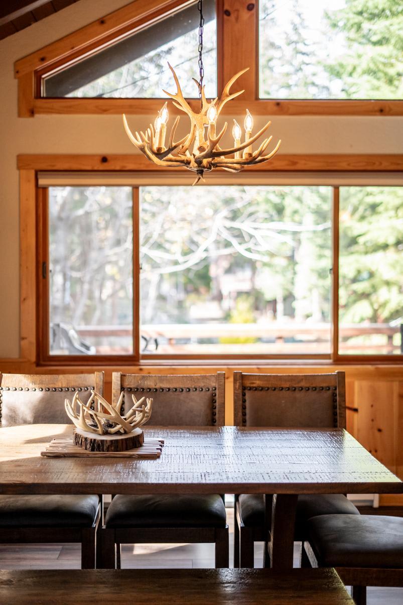 Dining area in Truckee vacation rental with antler chandelier and large window view.