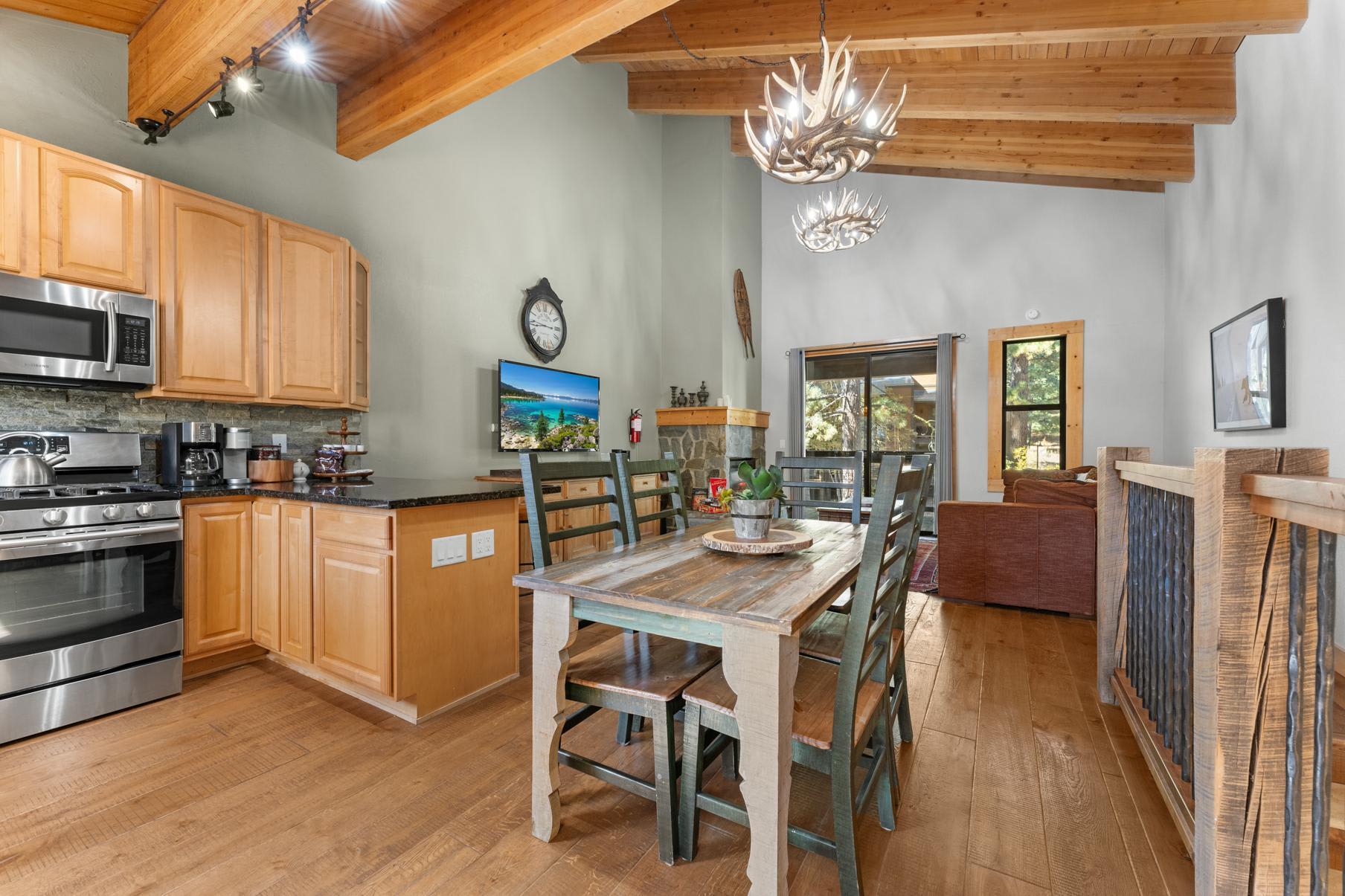 Rustic dining area and kitchen in a Truckee vacation rental with wood beams, antler chandeliers, and cozy furnishings.