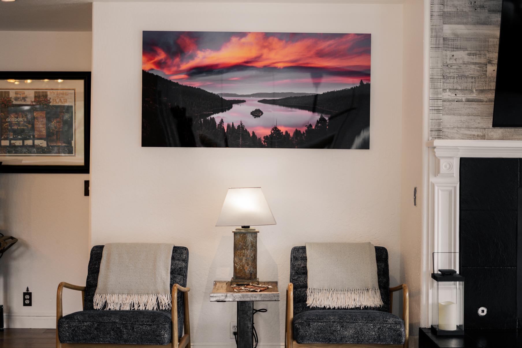 Cozy Truckee vacation rental with two cushioned chairs, a lamp, and striking sunset artwork on the wall.