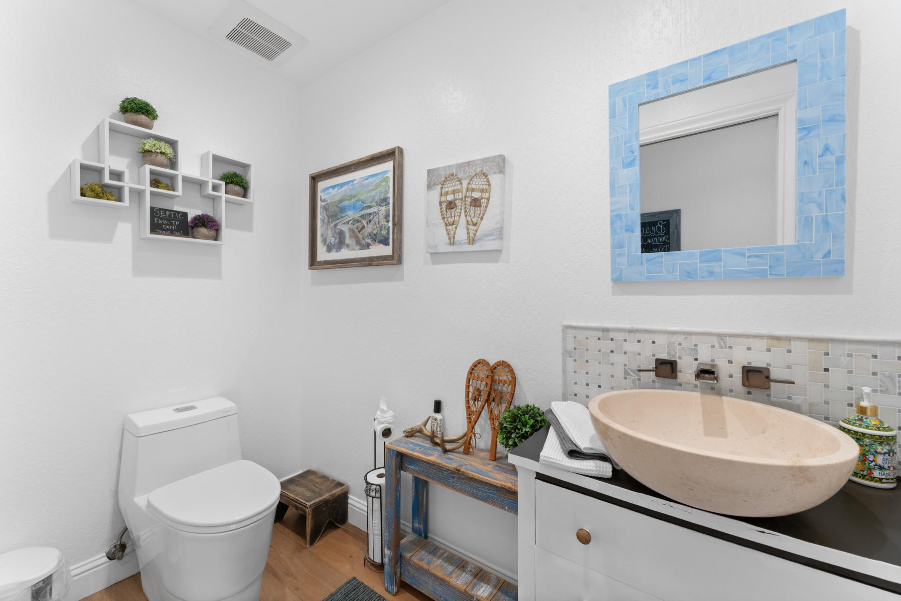 Bathroom of a Truckee vacation rental with modern decor, wall art, and a unique stone sink.