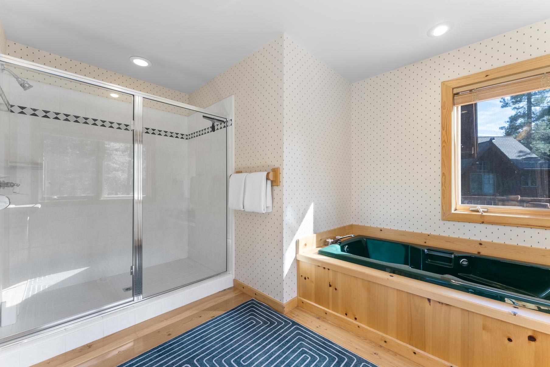 Bathroom in a Truckee vacation rental with a glass shower and a wooden bathtub featuring outdoor views.