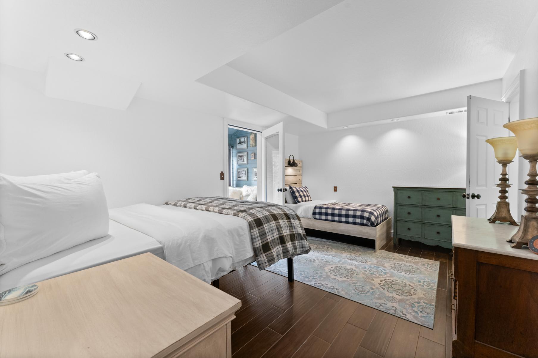 Bedroom in a Truckee vacation rental with two beds, wooden furniture, and a decorative rug, exuding a cozy, inviting atmosphere.