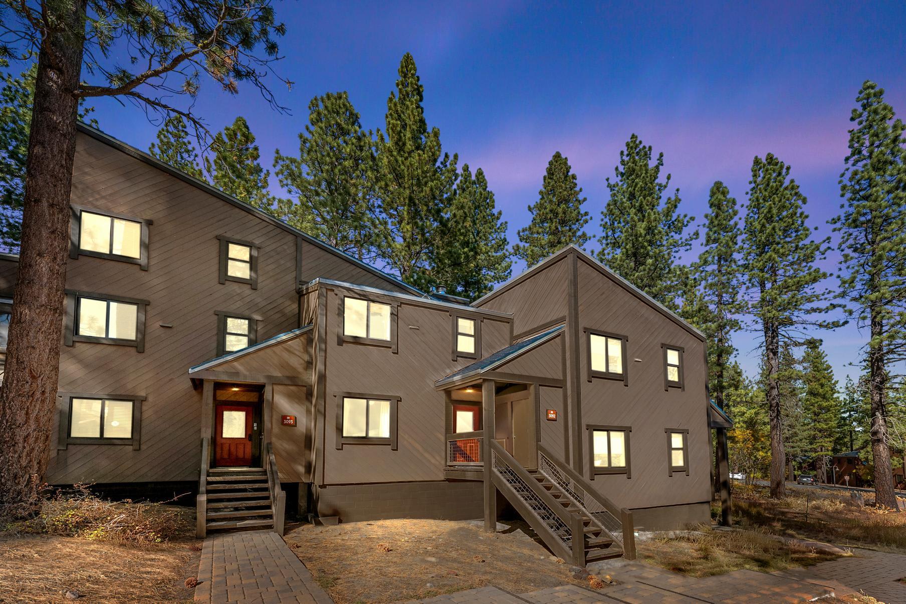 Brown vacation rental in Truckee surrounded by tall pine trees under a dusky sky.