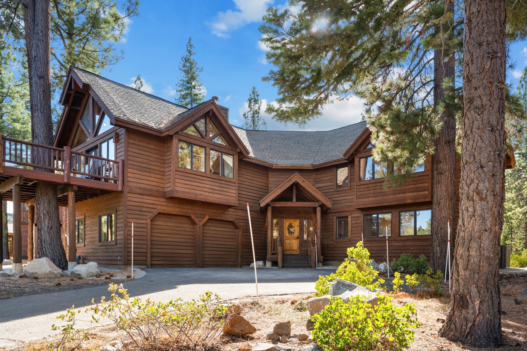 Wooden cabin-style vacation rental with large windows surrounded by pine trees in Truckee.