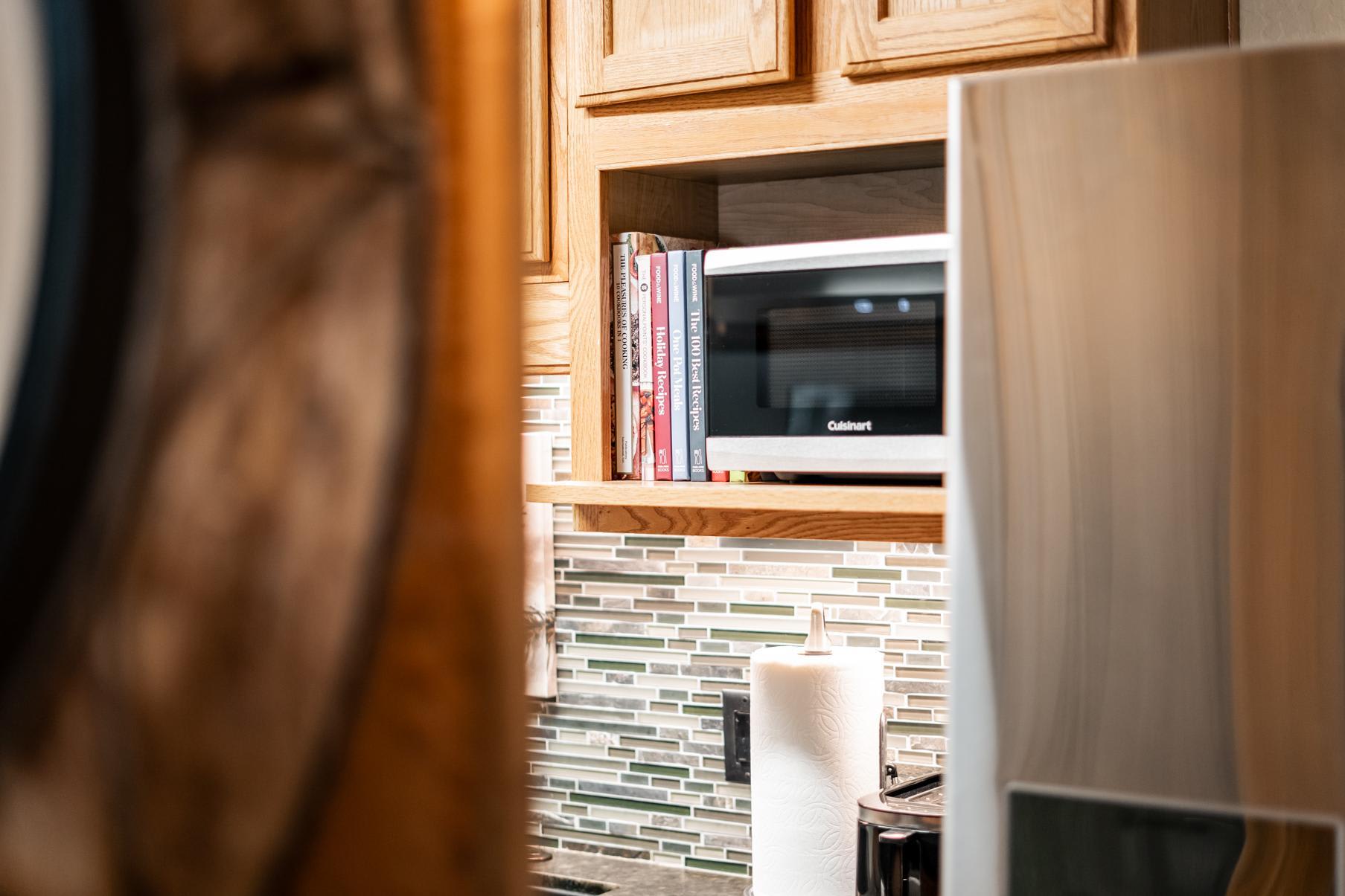 Kitchen scene in a Truckee vacation rental with a microwave, cookbooks, and mosaic tile backsplash.